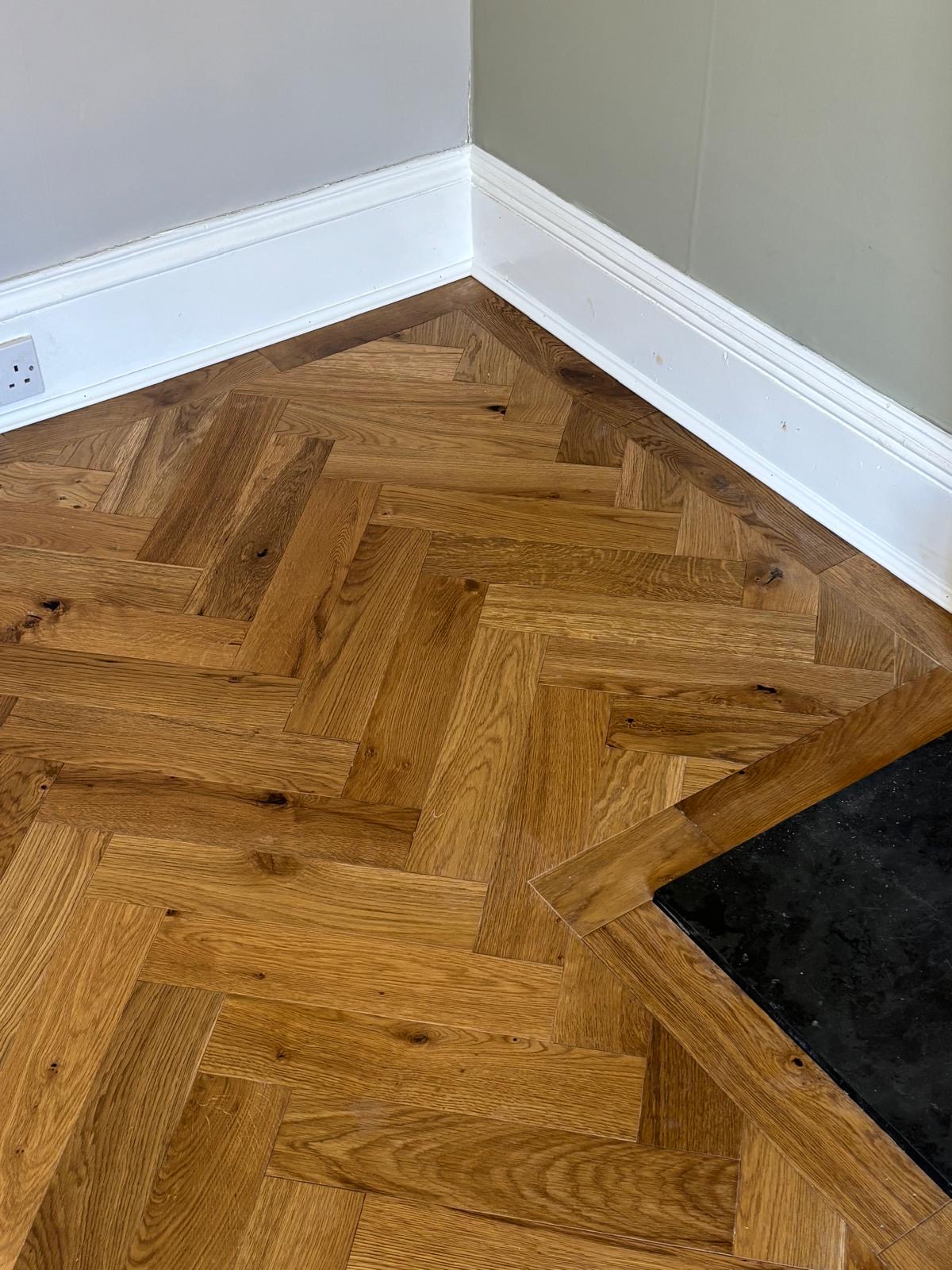 Close-up of herringbone boards and perimeter border beside white skirting