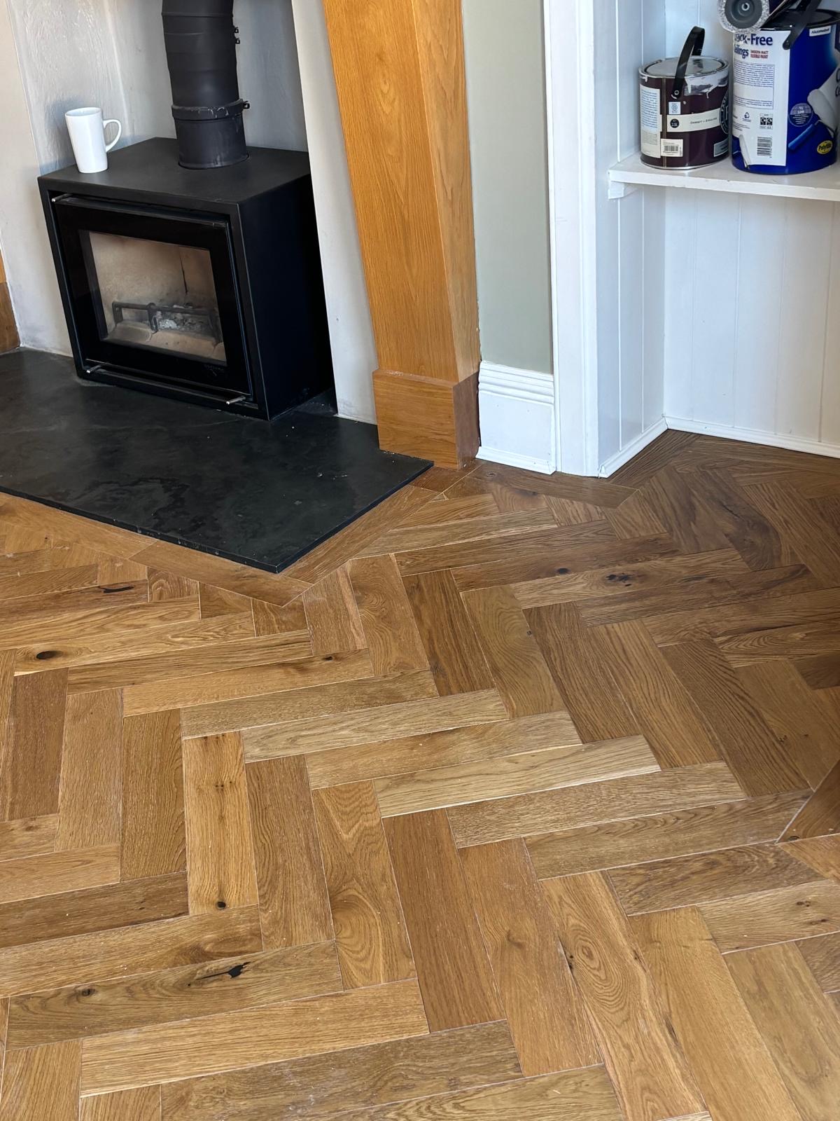Herringbone timber flooring fitted around a dark fireplace hearth