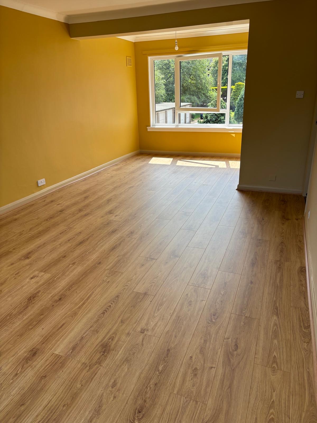 Sunlit engineered oak flooring in a yellow-walled room